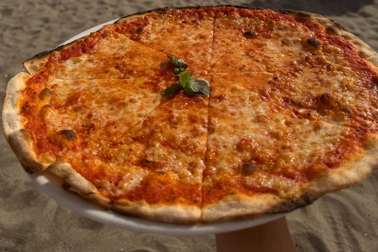 Freshly baked pizza at the Marechiaro restaurant and pizzeria, with the sea at Ostia behind